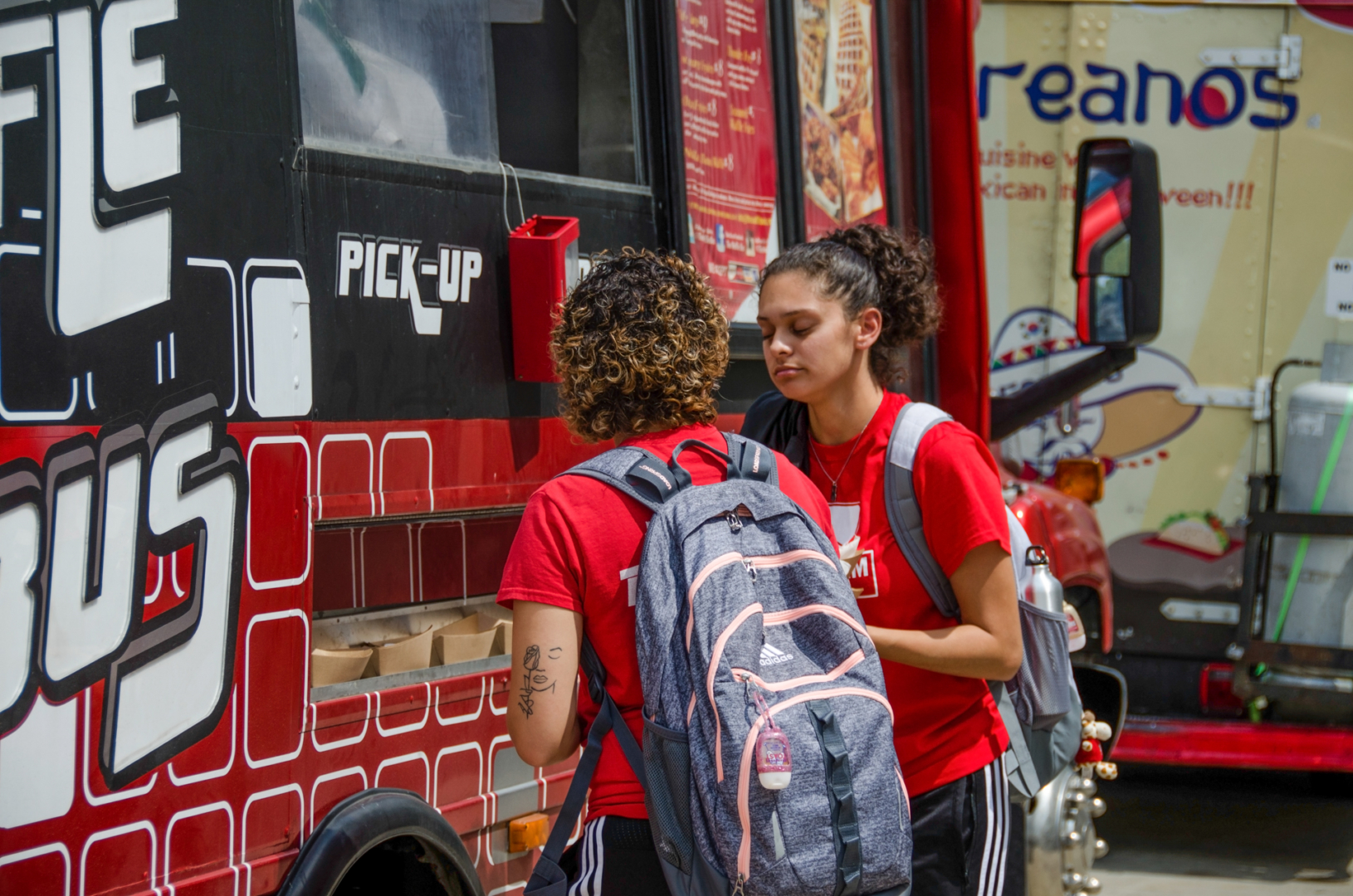 Two students stand in front of the Waffle Bus food truck