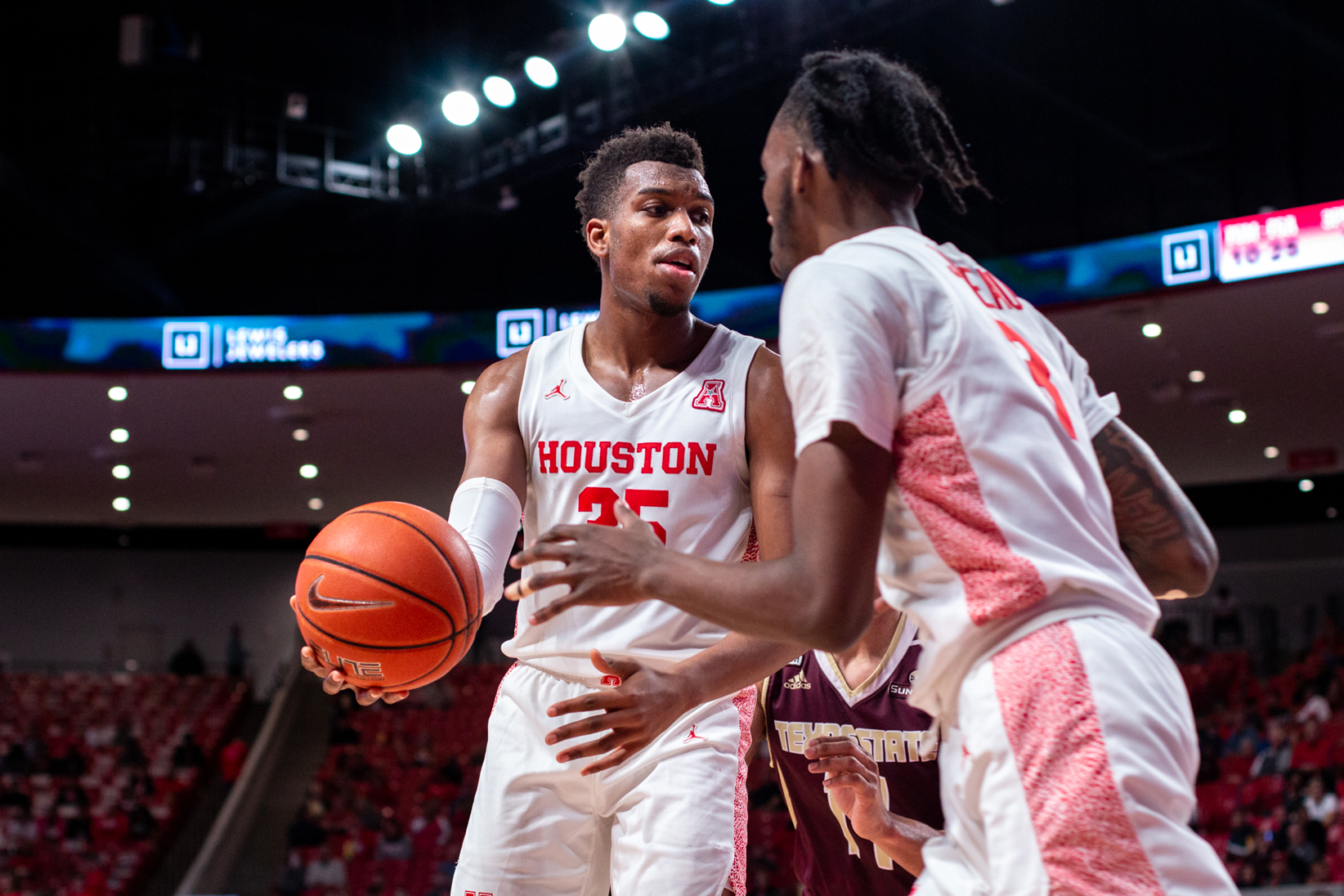 Junior forward Fabian White Jr. hands the ball off to DeJon Jarreau. White said team played with greater 'desperation' after the game in the win against SMU. | Kathryn Lenihan/ The Cougar
