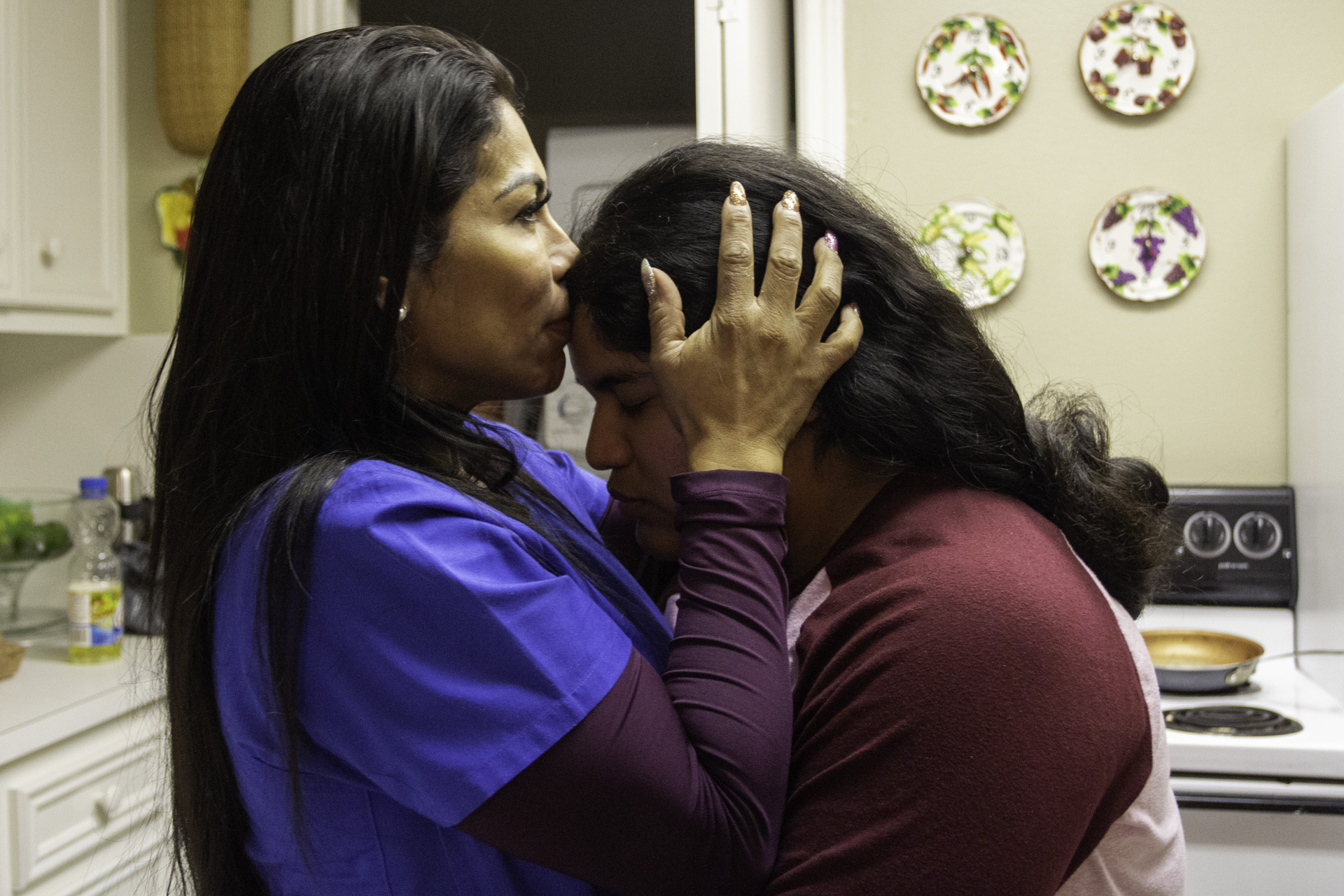 Magdalena Pineda (left) smells Celine Pineda's forehead, who is her daughter, in the kitchen of their Missouri City home. This is a traditional greeting within their Navajo tribe, according to Magdalena Pineda her people can smell the difference between someone who is their relative and those who are not. | Katrina Martinez/The Cougar