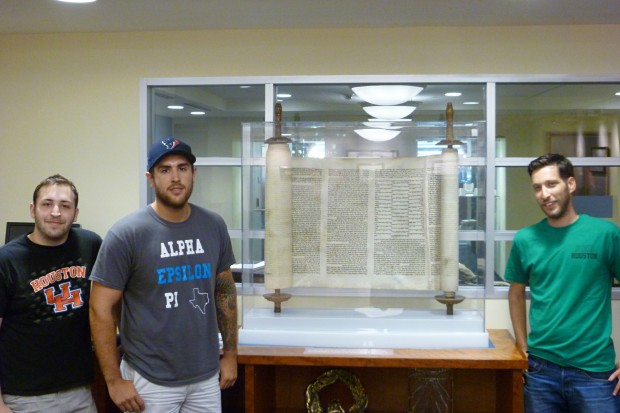 Brothers of Alpha Epsilon Pi fraternity, Jason Bravman and Matthew Boutin-Bloomberg (right) and Yuval Klein (left), pose for a picture in front of the Torah.  |  Image courtesy of Yuval Klein