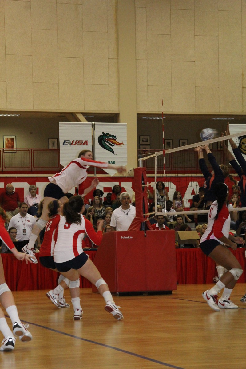 Katie Norris spikes a ball past Pepperdine defenders and teamates Natalie Keck and Olivia O’Dell prepare to return if necessary. | File photo/The Daily Cougar