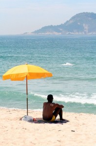 Man_sitting_under_beach_umbrella