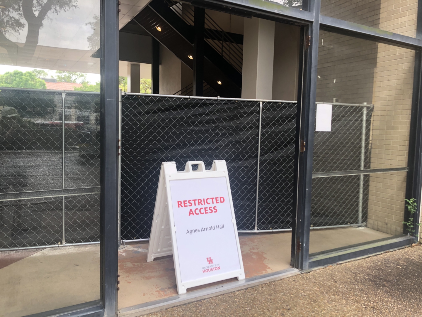 A sign reading "Access Restricted" in front of Agnes Arnold Hall.